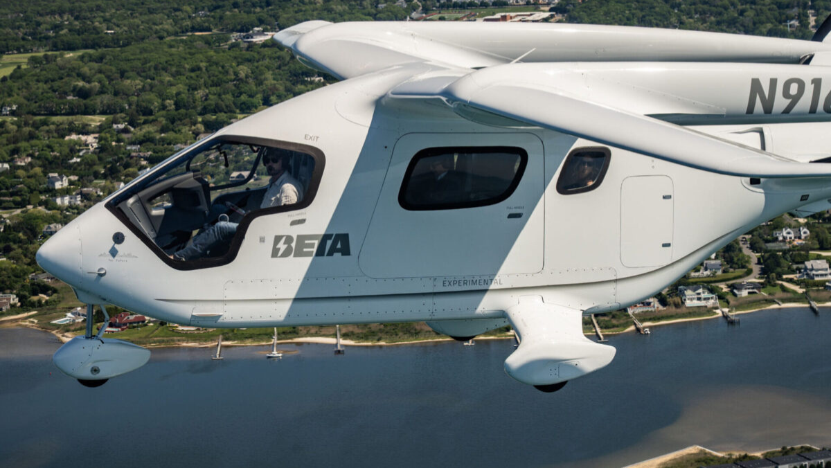 Experimental electric aircraft in flight over coastal landscape during test operation
