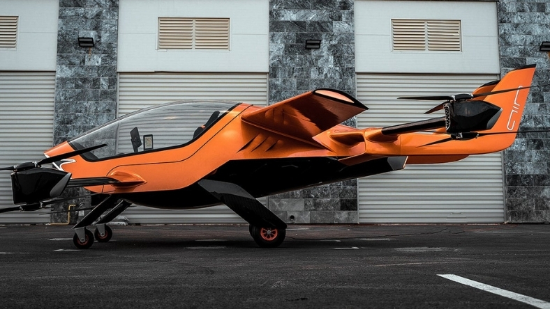 Orange AIR ONE electric aircraft displayed outside hangar